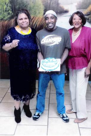 Photo of Zulu holding a birthday cake with his sisters